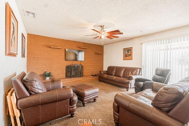 living room with carpet floors, a textured ceiling, ceiling fan, and visible vents