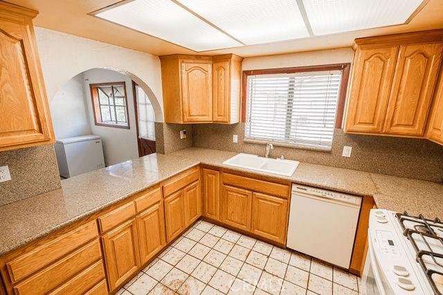 kitchen with decorative backsplash, gas range oven, arched walkways, a sink, and dishwasher