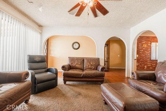 living area featuring arched walkways, a textured ceiling, ceiling fan, and a wealth of natural light