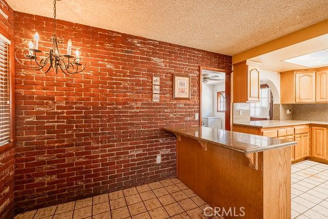 kitchen featuring light tile patterned flooring, brick wall, and light brown cabinets