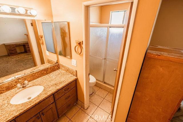 bathroom featuring vanity, tile patterned flooring, a stall shower, and toilet