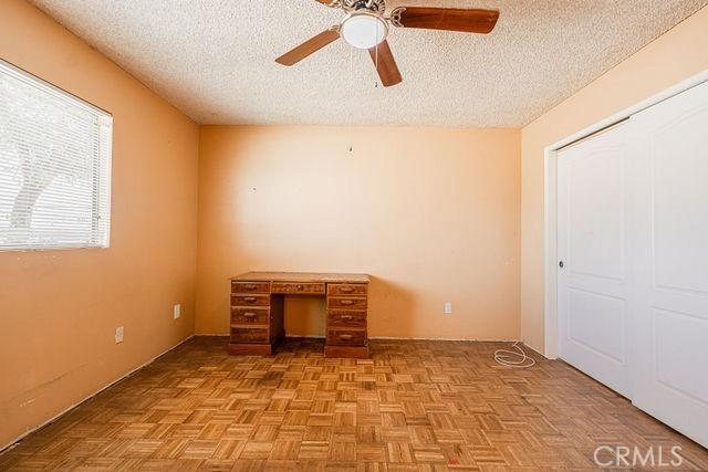 unfurnished bedroom with a ceiling fan and a textured ceiling