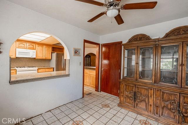 interior space with decorative backsplash, white appliances, ceiling fan, arched walkways, and light tile patterned floors