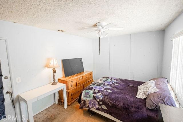 bedroom with visible vents, a textured ceiling, and ceiling fan