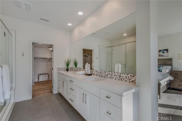 bathroom featuring double vanity, visible vents, a stall shower, a sink, and recessed lighting