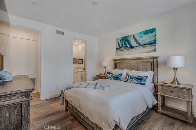 bedroom featuring connected bathroom, baseboards, visible vents, and wood finished floors