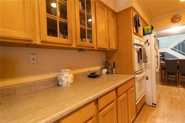 8060 Canby Ave Unit 2, Reseda, CA 91335 - kitchen with crown molding, light countertops, glass insert cabinets, light wood finished floors, and white appliances