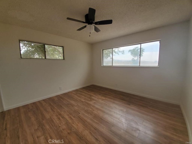 spare room with baseboards, a textured ceiling, and wood finished floors