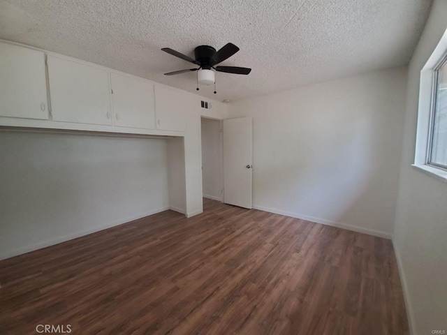 unfurnished bedroom featuring dark wood-style flooring, ceiling fan, a textured ceiling, visible vents, and a closet