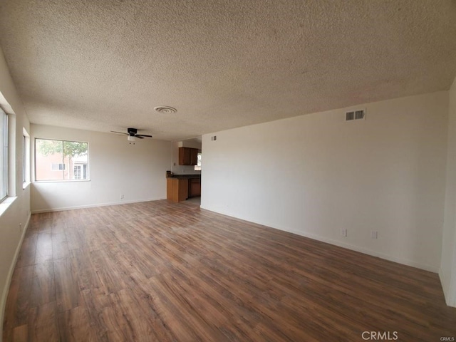 unfurnished living room featuring a textured ceiling, a ceiling fan, baseboards, wood finished floors, and visible vents