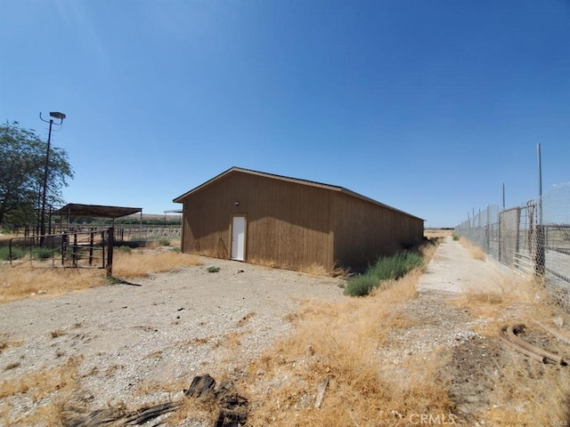 view of outbuilding with fence and an outbuilding