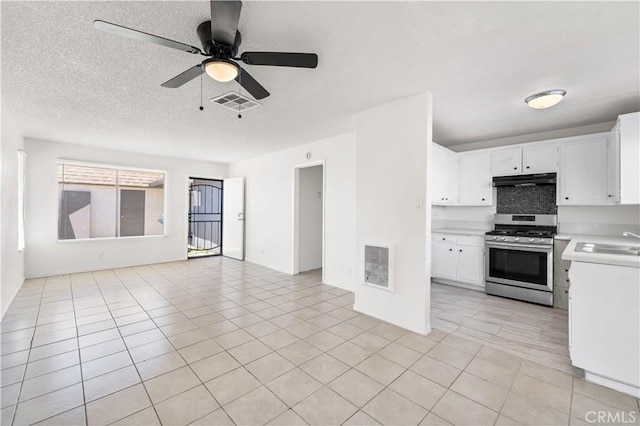 interior space with light countertops, white cabinets, stainless steel range with gas cooktop, open floor plan, and under cabinet range hood