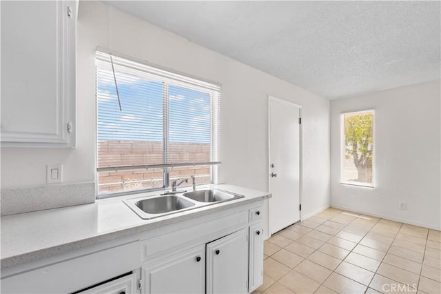 kitchen featuring a sink, light countertops, white cabinets, and light tile patterned floors