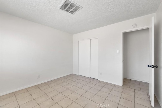 unfurnished bedroom featuring visible vents, a textured ceiling, light tile patterned floors, and a closet