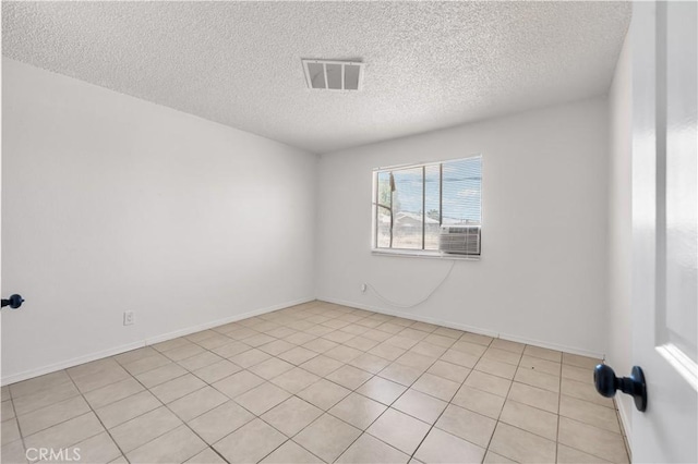 unfurnished room with light tile patterned floors, baseboards, a textured ceiling, and visible vents