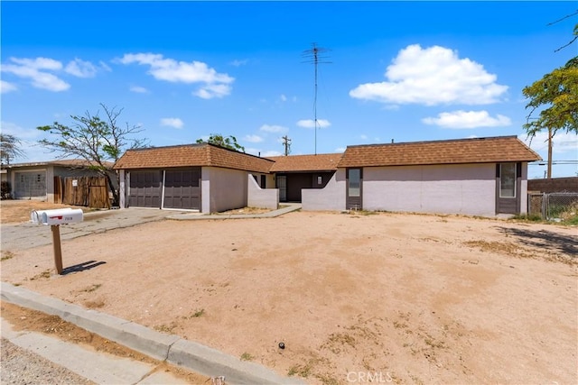 single story home featuring fence, a garage, stucco siding, mansard roof, and driveway