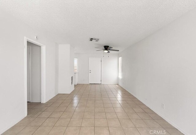 spare room featuring light tile patterned floors, a ceiling fan, a textured ceiling, and visible vents