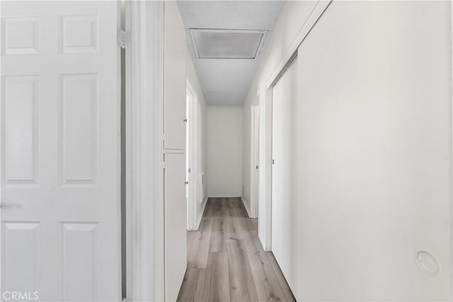 corridor featuring attic access and light wood finished floors