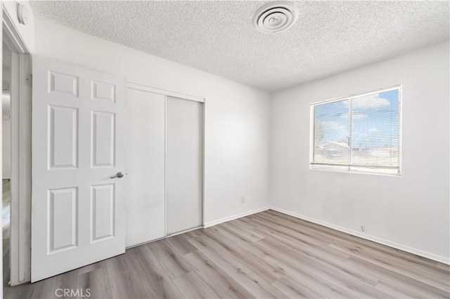 unfurnished bedroom featuring a textured ceiling, wood finished floors, and visible vents