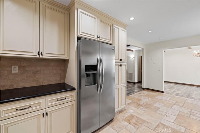 kitchen with decorative backsplash, dark countertops, recessed lighting, cream cabinetry, and stainless steel fridge with ice dispenser