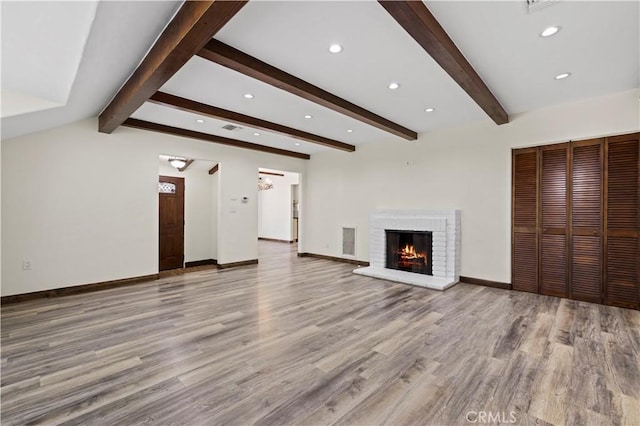 unfurnished living room with visible vents, beam ceiling, a fireplace, and light wood-type flooring
