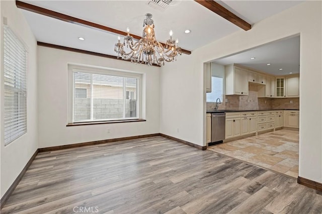 unfurnished dining area featuring an inviting chandelier, a sink, light wood-style flooring, baseboards, and beamed ceiling