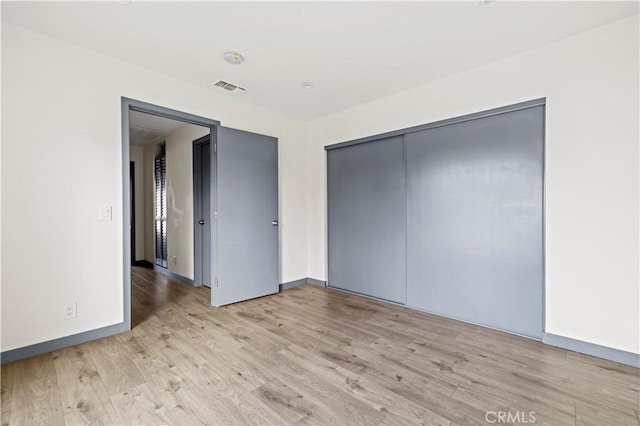 spare room with baseboards, visible vents, and light wood finished floors