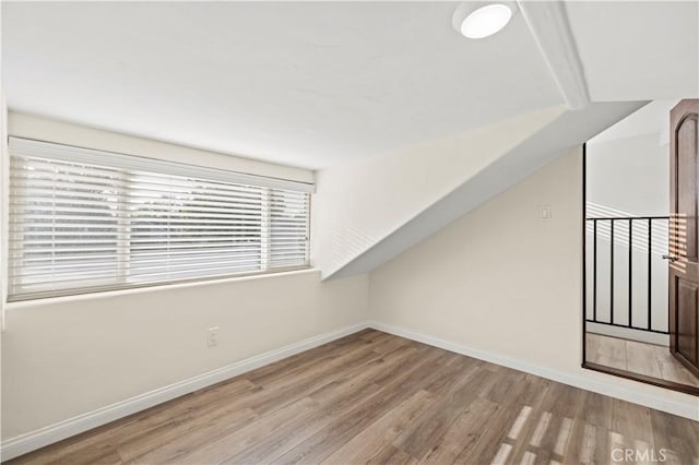 bonus room featuring baseboards and wood finished floors