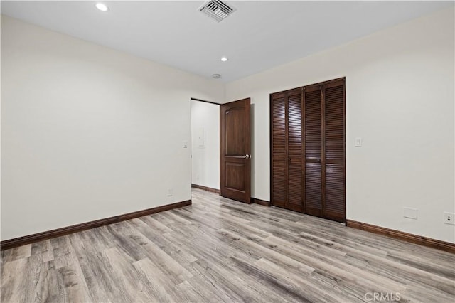 unfurnished bedroom featuring baseboards, a closet, light wood-style flooring, and visible vents