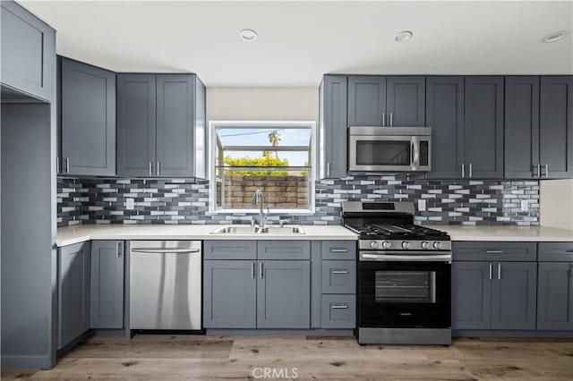 kitchen featuring a sink, appliances with stainless steel finishes, gray cabinetry, and light countertops