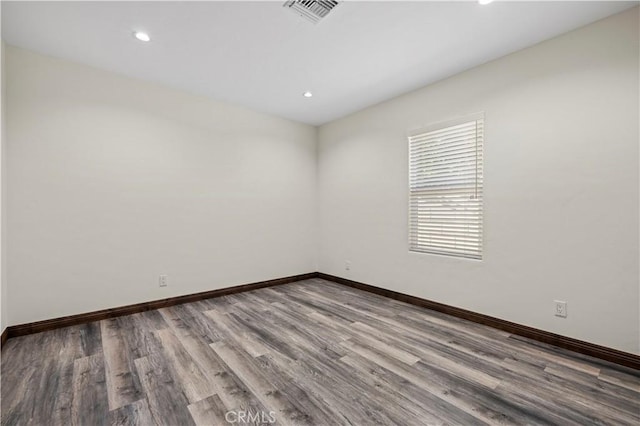 empty room with baseboards, recessed lighting, wood finished floors, and visible vents