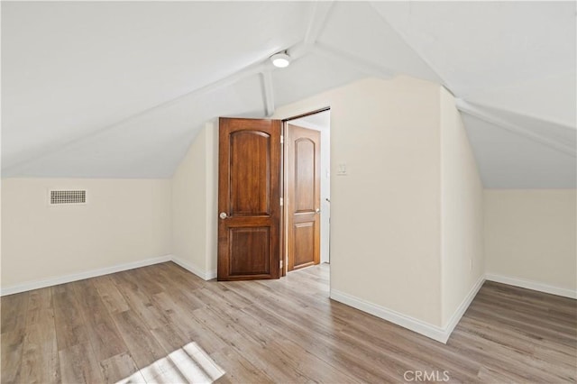 bonus room featuring baseboards, visible vents, vaulted ceiling, and light wood-style floors