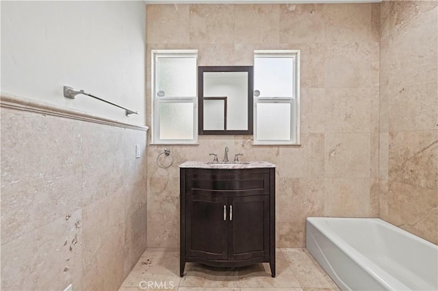 full bath featuring vanity, a washtub, and tile walls