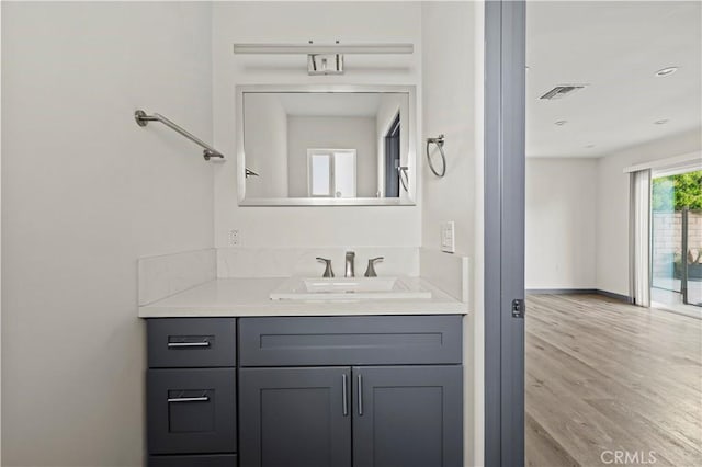 bathroom featuring baseboards, visible vents, wood finished floors, and vanity