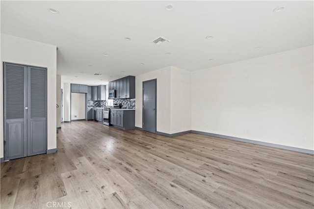 unfurnished living room featuring baseboards, visible vents, and light wood finished floors