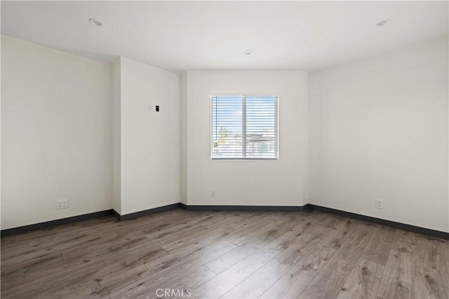 spare room with baseboards and wood finished floors