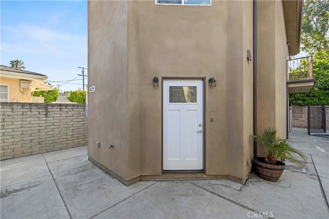 view of exterior entry with a patio and stucco siding