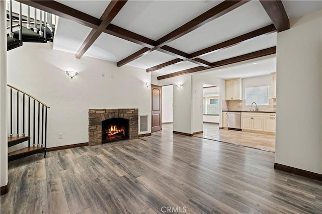 unfurnished living room featuring baseboards, light wood-style flooring, and beamed ceiling