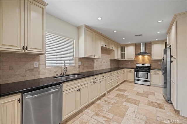 kitchen featuring appliances with stainless steel finishes, cream cabinets, and wall chimney exhaust hood