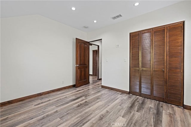 unfurnished bedroom with baseboards, visible vents, light wood finished floors, and a closet