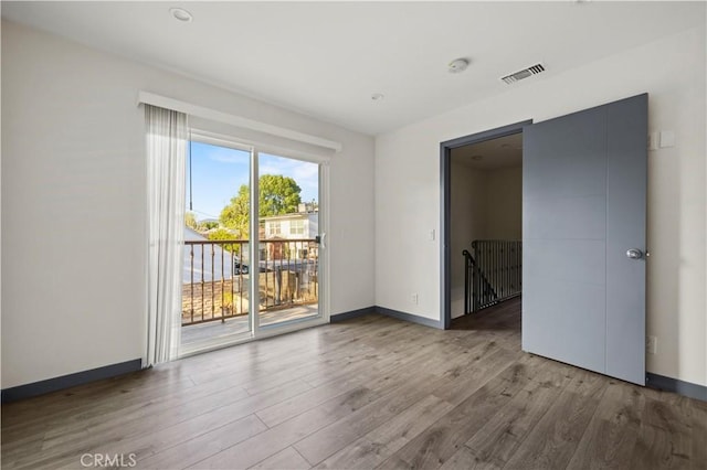 unfurnished room featuring baseboards, wood finished floors, and visible vents