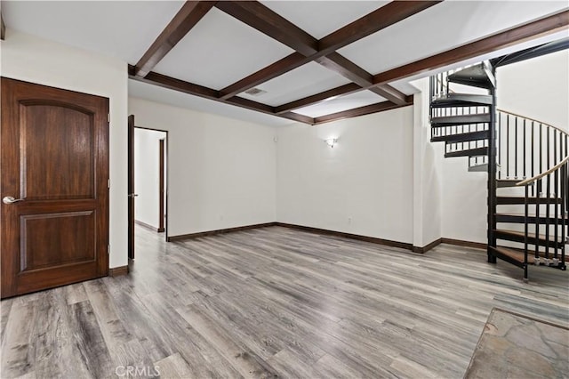 unfurnished living room featuring baseboards, light wood-style flooring, beam ceiling, and stairway