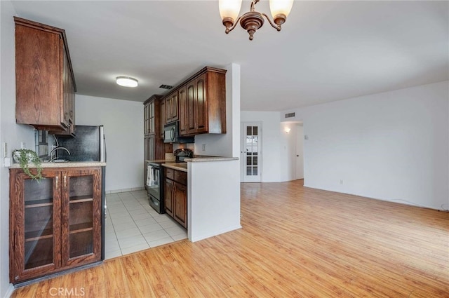 5400 Newcastle Ave Unit 56, Encino, CA 91316 - kitchen with visible vents, light countertops, a chandelier, light wood finished floors, and black appliances