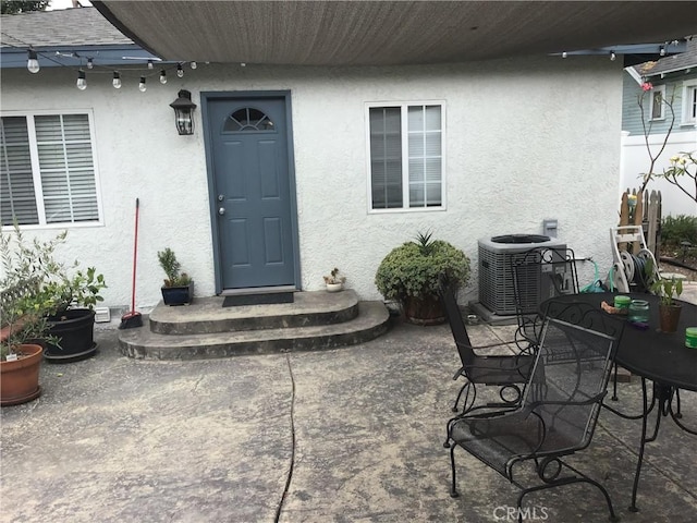 doorway to property with a patio area, stucco siding, and cooling unit