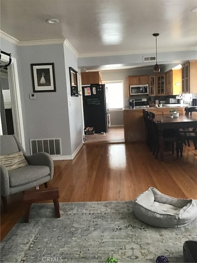 living room with visible vents, crown molding, and wood finished floors