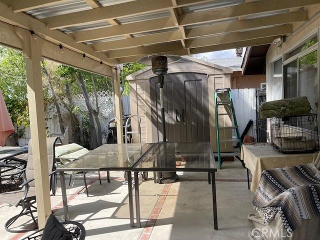 view of patio featuring a storage shed, fence, an outdoor structure, and outdoor dining area
