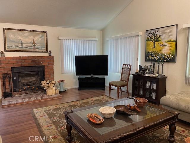 living area featuring wood finished floors, vaulted ceiling, and a fireplace