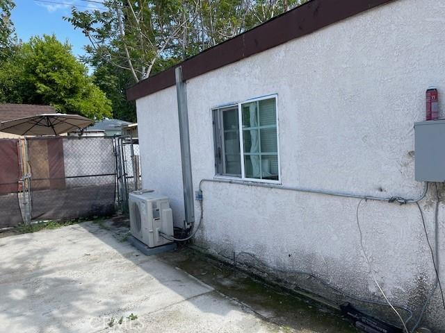 view of side of home with fence, a patio, ac unit, and stucco siding