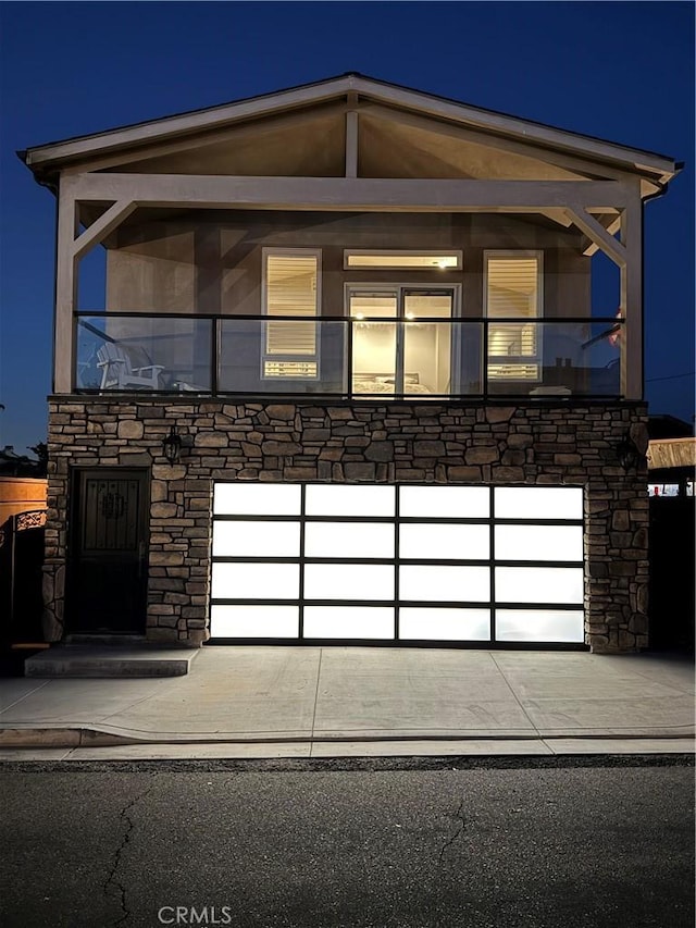 contemporary house with a garage, driveway, and stone siding