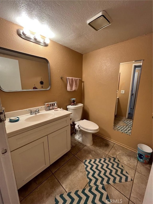 bathroom with vanity, a textured wall, tile patterned floors, and toilet